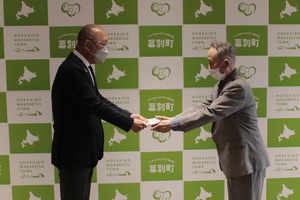 飯田町長が寄付金を受け取っている様子