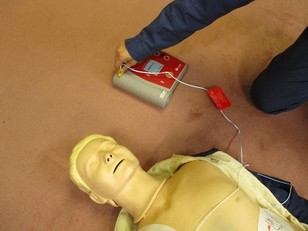 電極パッドのケーブルコネクタをAED本体の差込口にさしている様子