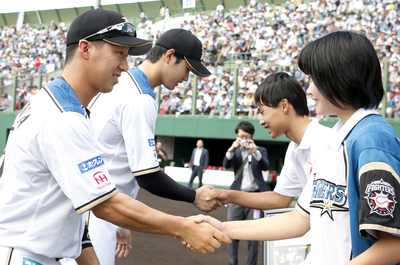 久保さんと稲川さんが選手と握手をしている写真