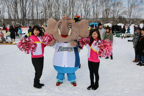 日本ハムファイターズのユニフォームを着たパオくんと記念撮影する松田佳月さん(左)と、安念莉紗子さん(右)